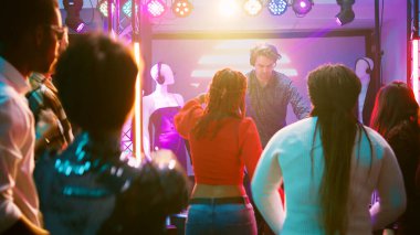 Çılgın DJ sahneye atlıyor, ritimleri karıştırıyor, gece kulübündeki insanlarla eğleniyor. Genç erkekler ve kadınlar birlikte eğleniyor ve elektronik müzik eşliğinde dans ediyorlar. El kamerasıyla..