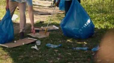 Çeşitli gönüllüler çöpleri ve maşayla plastik çöpleri topluyor, yasadışı atıklarla savaşmak ve doğal orman ortamını korumak için çalışıyorlar. Eylemciler çöp temizliği için gönüllü oluyorlar. Kamera A.