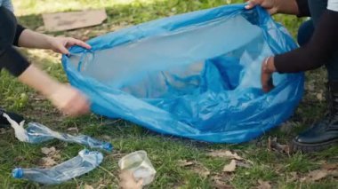 Geri dönüşüm için çöp ve plastik atık toplayan aktivistlerden oluşan bir ekip çöp temizleme araçları ve çöp torbalarıyla ormanı temizliyor. Ormandan çöp toplayan insanlar, aktivizm. Kapatın. Kamera A.