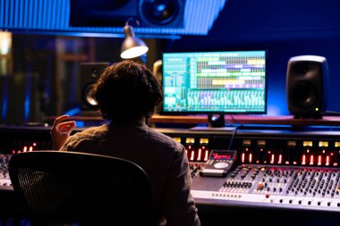 Ses uzmanı kontrol odasında daw yazılım arayüzü ile müzik düzenleme, işleme ve karıştırma üzerinde çalışıyor. Kontrol paneli konsolunda çalışan yetenekli mühendis, karıştırıcı istasyonu.