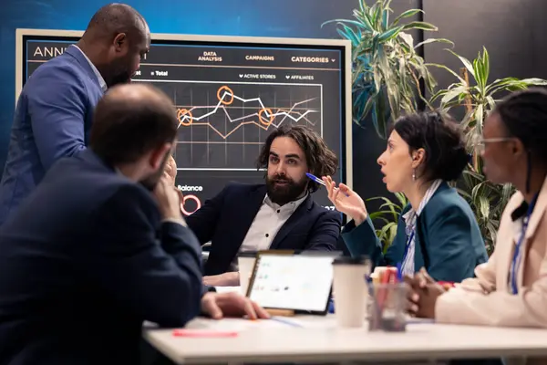 stock image Teammates reviewing sales infographics on interactive board presentation, look into annual reports to understand what needs to change in order to expand the organization internationally.