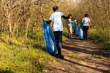 Afro-Amerikan iklim değişikliği gönüllüsü çöp torbalarını toplayarak doğal çevreyi korumaya çalışıyor. Doğanın korunması ve toplum hizmeti için gönüllü olmak.