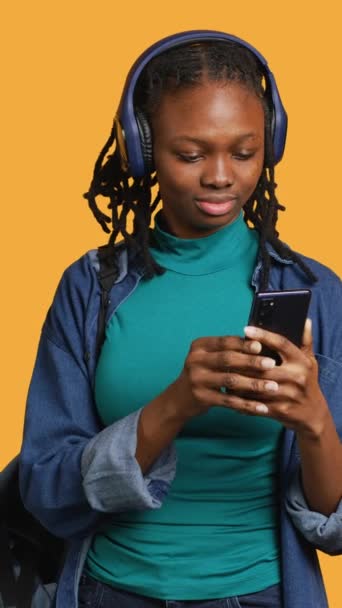 在视频会议期间 非裔美国青少年通过电话和耳机 工作室背景与朋友交谈 Bipoc的年轻女孩在网上视频节目中与伴侣聊天 — 图库视频影像