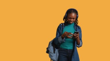 Afrikalı Amerikalı genç, ödeme metodunu web sitesine ekliyor, stüdyo arka planında izole edilmiş. Kulaklık takan, internet alışverişi yapan, kredi kartı bilgilerini telefonla yazan, B kameralı genç bir kız.