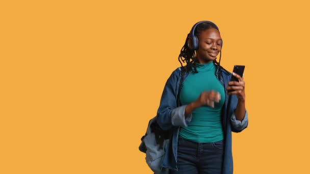 African American Teenager Talks Friends Videoconference Using Phone Headphones Studio — Stock Video