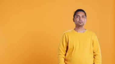 Gülümseyen, mutlu görünen, sarı stüdyo arka planında izole edilmiş neşeli Hintli bir adamın portresi. Mutlu Asyalı insan sırıtıyor, tatmin olmuş hissediyor, kamera B