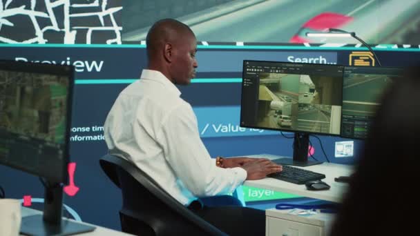 操作员用卫星导航图指导送货卡车司机 在观察室工作以避免交通拥挤 监视系统内的非裔美国人雇员追踪令相机A — 图库视频影像