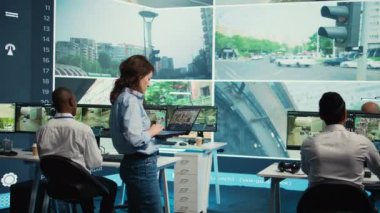 Ekip lideri şehir trafiğini büyük bir ekrandan izliyor. Halkın güvenliğini sağlamak için gerçek zamanlı güvenlik kamerası görüntülerini kullanıyor. Teşkilat, CCTV güvenlik sistemini denetliyor. Kamera B.