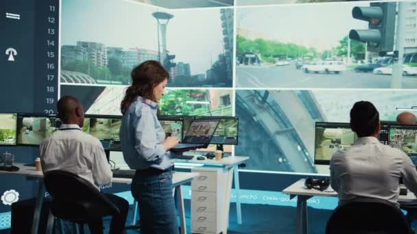 チームリーダーは 公共の安全を確保するためにリアルタイムの監視映像を使用して 大きな画面上の彼女の多様なチームとの都市交通を監視します Cctvのセキュリティシステムを監督する機関 カメラ — ストック動画