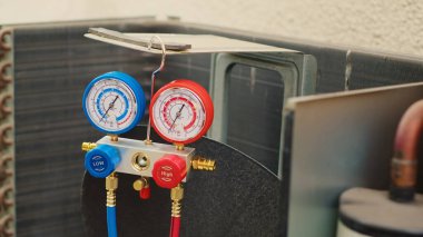 Zoom out shot of broken pressure measurement device used for checking hvac system freon pressure, in need of repair. Set of manifold meters showing high or low refrigerant levels