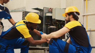 Hvac sistemindeki sıvı ve gazları kontrol etmek için profesyonel basınç kriterleme aracı oluşturma konusunda uzman olan Afro-Amerikan tamirci yoğunlaştırıcıdaki toprak ve toz katmanlarını temizlerken,