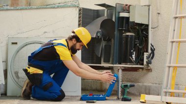 Rutin hvac sistem bakımı için görevlendirilmiş yetenekli bir mühendis işe başlamadan önce manometre montajı yapıyor. Tamirci soğutma verimliliğinin azalmasına yol açan soğutucu sızıntıları arıyor.
