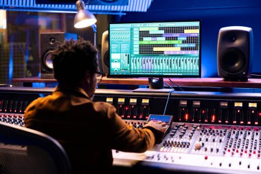 Afrika kökenli Amerikalı ses uzmanı ses ayarlarını, kontrol odasını ve karıştırma konsolunu ayarlamak için yazılımı çalıştırıyor. Profesyonel teknisyen albüm için yeni parçalar yaratıyor.