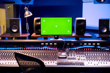 Yeşil ekran izole monitörlü boş stüdyo kontrol odası, profesyonel panel paneli ve müzik sonrası yapımında kullanılan teknik ekipman. Ses panosunda dengeleyici ve kaydırıcılar.