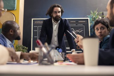 İş ortakları, üretkenliği ölçmek için başarı ölçümleri ve kilit performans göstergelerini gözden geçirmek üzere bir kurul odasında yeni bir proje üzerinde birlikte çalışıyorlar. Girişim hedeflerine ulaşan meslektaşlar.