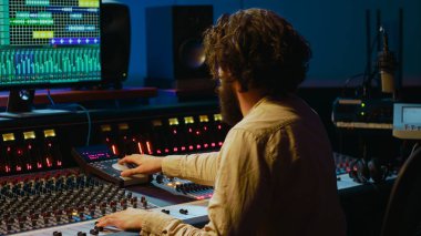 Müzik yapımcısı stüdyoda konsol ve ses yazılımlarını karıştırarak şarkıları düzenliyor, tuşlara basıyor ve kontrol odasındaki düğmeleri çeviriyor. Ses mühendisi melodi üretiyor ve sesi ayarlıyor. Kamera A.