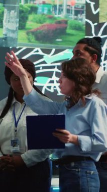 Vertical Video Diverse çalışanları grubu sipariş teslimatını hızlandırmanın yollarını tartışıyor, uydu navigasyonunda trafikten kaçınmak için yollar arıyorlar. Ajans operatörleri izleme odasında kamera görüntülerini kullanıyorlar.