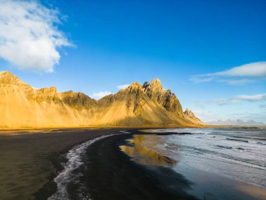 Stoksnes plajı, nefes kesen dondurucu soğuk doğal ortamda Vestrahorn dağ zincirine ev sahipliği yapar. Dik kenarları ve İzlanda denizleri olan İskandinav kıyıları manzarası. Hava görünümü.