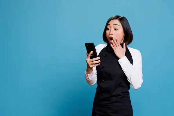 Podekscytowana Azjatycka Recepcjonistka Zakrywająca Usta Zaskakującym Gestem Czytając Pozytywne Opinie Zdjęcia Stockowe bez tantiem