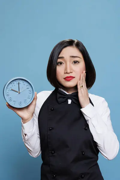 Upset Asian Waitress Showing Alarm Clock Looking Camera Disappointed Facial Stock Photo