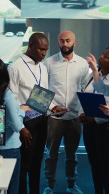 Vertical Video Diverse çalışanları grubu sipariş teslimatını hızlandırmanın yollarını tartışıyor, uydu navigasyonunda trafikten kaçınmak için yollar arıyorlar. Ajans operatörleri izleme odasında kamera görüntülerini kullanıyorlar.