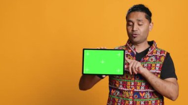 Stüdyo arka planında izole edilmiş yeşil ekran tableti kullanarak Hintli bir adamın portresi pazarlama yapıyor. Gülen kişi elinde boş fotokopi aleti, kamera A
