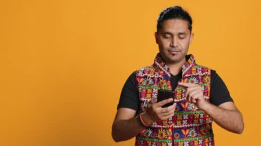 Akıllı telefonda video oyunu oynayan mutlu bir adam düşmanları yendikten sonra kutlama yapıyor, el hareketi yapıyor. Oyuncu telefon ekranı araklıyor. Maçı kazanmak için heyecanlanıyor. Stüdyo arka planı, kamera A.