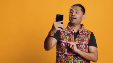 Mutlu bir adam, arkadaşlarıyla internet üzerinden telefon görüşmesi yapıyor, dostça jestler yapıyor. Telekonferansta arkadaşınla iletişim kurarken gülümseyen kişi cep telefonu, stüdyo arka planı, kamera A