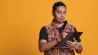Adam alışveriş sitesine tablet kullanarak ödeme metodu ekliyor, promosyonlardan faydalanıyor, stüdyo geçmişi kullanıyor. Hintli kişi internetten bir şeyler alıyor, kredi kartı kullanıyor, cihaza veri yazıyor, kamera A