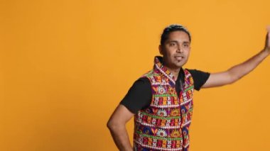 Neşeli insan eğleniyor, oryantal müzik eşliğinde dans ediyor, dinlenme zamanının tadını çıkarıyor. Neşeli adam Bollywood dans figürleri yapıyor, stüdyo arka planında izole edilmiş, kamera A