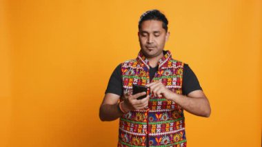 Akıllı telefonda video oyunu oynayan mutlu bir adam düşmanları yendikten sonra kutlama yapıyor, el hareketi yapıyor. Oyuncu telefon ekranını araklıyor. Maçı kazanmaktan heyecan duyuyor. Stüdyo arka planı, kamera B