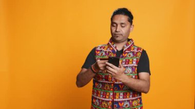 Hintli adam cep telefonu sitesine ödeme metodu ekliyor, bir şeyler satın alıyor, stüdyo arka planında izole edilmiş. Müşteri internet alışverişi yapıyor, cep telefonu ve kamera B 'de banka kartı bilgileri yazıyor.