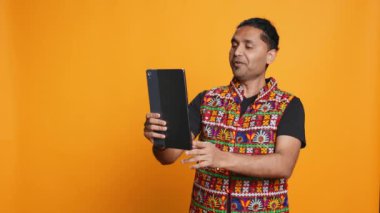 Rahatlamış bir adam, arkadaşıyla internetten görüntülü konuşma yapıyor. Kaygısız Hintli arkadaşla telekonferansta tartışıyor tablet, stüdyo arkaplanı, kamera B
