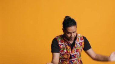 Geleneksel kıyafetler giymiş heyecanlı biri eğleniyor, doğu müziğiyle dans ediyor. Bollywood dans figürleri, stüdyo geçmişi, kamera A.