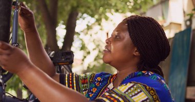 Özel iş aletleriyle bisiklet lastiği tamir ve ayarlama yapan aktif genç bir kadın. Sağlıklı spor düşkünü Afrikalı Amerikalı kadın profesyonel alet çantasıyla bisiklet tekerleğini sağlama aldı..