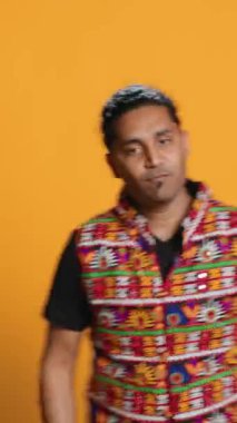 Dikey video ekstatik insan geleneksel Hint kıyafetleri giyerek enerjik dans adımları atıyor. Bollywood koreografisi hareketleri, stüdyo geçmişi, kamera A.