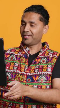 Dikey video rahatlamış adam, arkadaşlarıyla internetten görüntülü konuşma yaparken eğleniyor. Kaygısız Hintli arkadaşla telekonferansta tartışıyor. Tablet, stüdyo arka planı kullanarak.