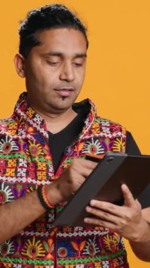 Dikey Videocu, tablet kullanarak alışveriş sitesine ödeme metodu ekliyor, promosyonlardan faydalanıyor, stüdyo geçmişini kullanıyor. Hintli kişi internetten kredi kartıyla bir şeyler alıyor, cihaza veri yazıyor