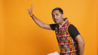 Neşeli insan eğleniyor, oryantal müzik eşliğinde dans ediyor, dinlenme zamanının tadını çıkarıyor. Neşeli adam Bollywood dans hareketleri yapıyor, stüdyo arka planında izole edilmiş, kamera B