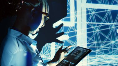 Yetersiz aydınlatılmış sunucu merkezini denetleyen, tablet üzerinde kod çalıştıran, sunuculardan, ağ sistemlerinden ve depolama dizilerinden oluşan teknolojik olarak gelişmiş makine kümeleri üzerinde kontrol yapan yetenekli denetleyici