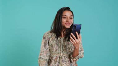 Telekonferans toplantısında gülümseyen bir kadın akıllı telefon ve stüdyo geçmişi kullanarak arkadaşça konuşmalar yapıyor. Hintli insan arkadaşlarıyla çevrimiçi video görüşmesi yaparken eğleniyor, kamera A