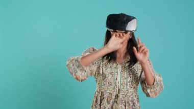Sanal gerçeklik kulaklığı takan Hintli kadın el kol hareketleri yapıyor. Teknoloji meraklısı ileri teknoloji modern VR aygıtı kullanıyor, stüdyo arka planında izole edilmiş, kamera A