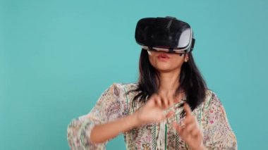 Sanal gerçeklik kulaklığı takan Hintli kadın el kol hareketleri yapıyor. Teknoloji meraklısı ileri teknoloji modern VR aygıtı kullanıyor, stüdyo arka planında izole edilmiş, kamera B