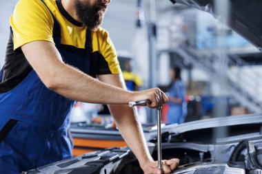 Araba servisindeki tamirci, frenleri değiştirdikten sonra vidaları sıkmak için tork anahtarı kullanır. Deneyimli oto tamircisi müşteri otomobilini tamir etmek için profesyonel araçlar kullanır.