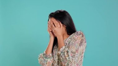 Korkak Hintli kadın avuçlarıyla yüzünü kapatıyor, tedirgin edici tehlikelerden korkuyor, stüdyo geçmişinden soyutlanmış. Tehlikeden korkan, güçlüklerle karşı karşıya kalan, güvensiz kişi, kamera B
