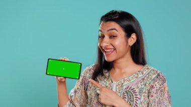Gülümseyen kadın izole edilmiş cep telefonu gösteriyor, promosyon yapıyor, stüdyo geçmişi var. Neşeli Hintli kişi reklam markaları için kullanılan fotokopi alanı model cep telefonunu tutuyor, kamera B