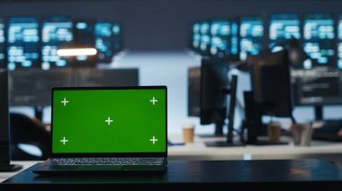 Focus on isolated screen laptop in data center with man in blurry background coding, managing server rows. Close up shot of chroma key notebook and IT expert overseeing rackmounts operating data clipart