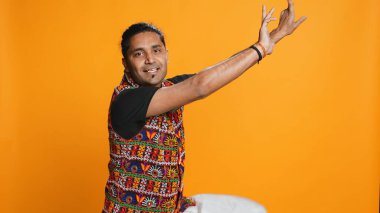 Neşeli insan eğleniyor, ritimli dans ediyor, işten izin günlerinin tadını çıkarıyor. Neşeli Hintli adam kendini eğlendirirken garip hareketler yapıyor, sallanan kollar, stüdyo arka planı, kamera B