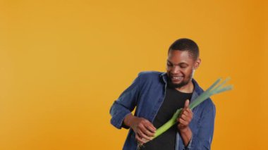 Stüdyoda pırasa çalarken eğlenen, garip davranan ve yeşil soğanı müzik aleti olarak taklit eden mutlu insan. Genç adam organik sebzelerle aptalca davranıyor. Kamera B.