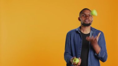 Stüdyoda olgun yeşil elmalarla hokkabazlık yapan oyuncu, fırlatarak ve yakalayarak sürekli hareket halinde tutuyor. Yetenekli adam organik meyvelerle eğleniyor. Kamera B.